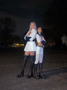 two young women dressed in costume posing for a photo at night with their arms around each other