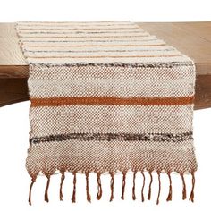 a brown and white striped table runner on top of a wooden table with a piece of wood