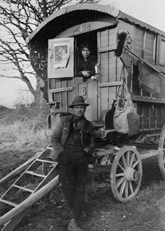 an old black and white photo of a man standing next to a horse drawn wagon