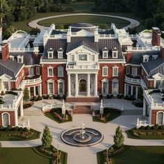 an aerial view of a large red brick mansion with fountain in the center and landscaping around it