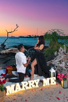 a man kneeling down next to a woman on the beach