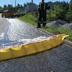 a man standing next to a yellow banana laying on the side of a road with water coming out of it