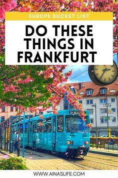 a blue train traveling down tracks next to a tree with pink flowers on it and the words europe bucket list do these things in frankfurt