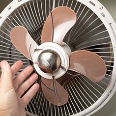 a person is holding a small fan in their hand while they are working on it