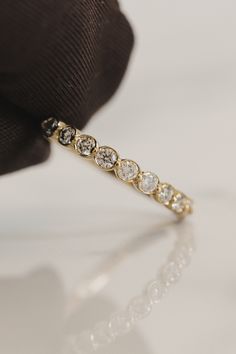 a diamond ring sitting on top of a white table next to a black tie and brown cloth