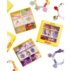 an assortment of assorted jewelry in a yellow box on a white surface with other items surrounding it