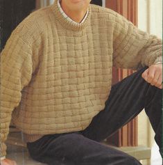 a man wearing a sweater and pants sitting on a step with his hands in his pockets