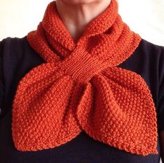 a woman wearing an orange knitted scarf with a knot around her neck and black shirt underneath