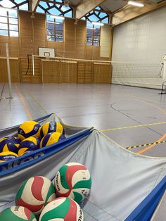 several balls are stacked on top of each other in an indoor basketball court with net