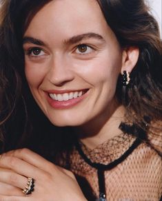 a smiling woman with her hands on her chest and wearing an elegant ring in front of her face