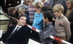 a man in a suit and tie standing next to a group of children holding a ribbon