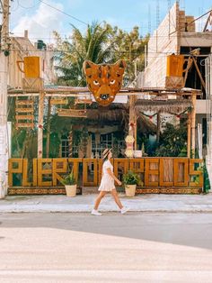 a woman walking down the street in front of a building with an animal head on it