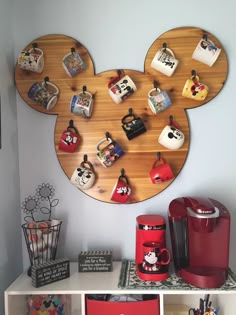 a mickey mouse clock on the wall next to some cups and other items in front of it