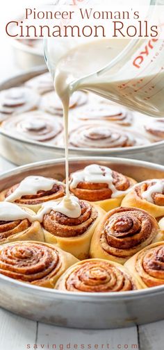 a pan filled with cinnamon rolls being drizzled with white icing on top