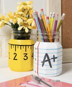 two mason jars with pencils, rulers and yellow daffodils in them