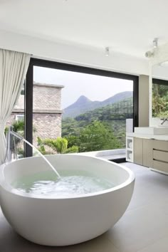 a large white bath tub sitting inside of a bathroom next to a sink and window