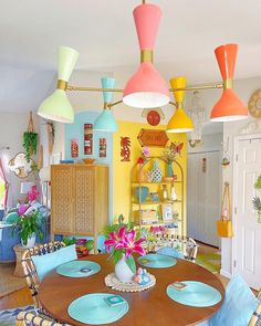 a dining room table with blue chairs and colorful lights hanging from it's ceiling