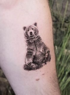 a small bear tattoo on the left arm