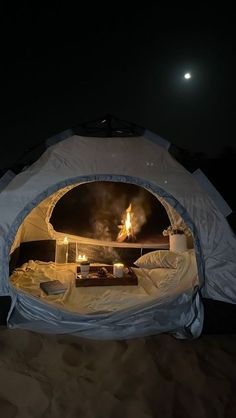 the inside of a tent that is lit up at night with candles in it and some blankets on top