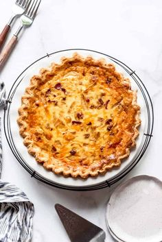 a pie sitting on top of a white plate next to a fork and spoons