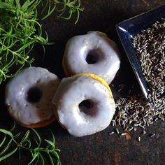 three glazed donuts with sprinkles next to some grass and a plate