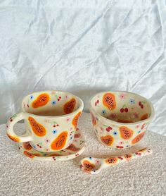 two cups and saucers with fruit designs on them