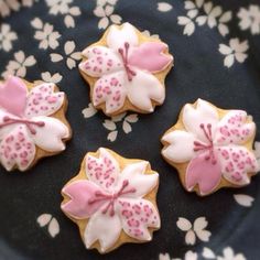 three decorated cookies sitting on top of a black and white floral plate with pink flowers