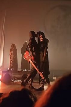 two people standing on stage with one holding a guitar