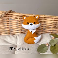 a stuffed fox sitting on top of a pillow next to a wicker basket with leaves