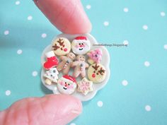 a hand holding a small white plate with christmas cookies on it and snowmen around it