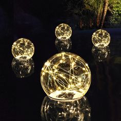 three glass orbs with lights on them in the dark