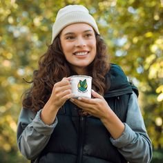 a woman holding a coffee cup in front of her face and smiling at the camera