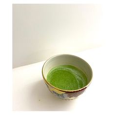 a bowl filled with green liquid sitting on top of a white counter next to a wall