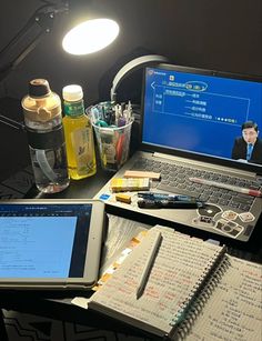 an open laptop computer sitting on top of a desk next to a notebook and pen