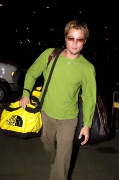 a man carrying a yellow duffel bag in his hand