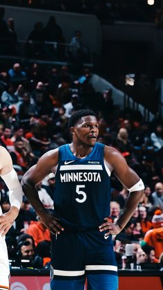 minnesota basketball players standing on the court with their hands on their hipss while fans watch