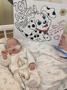 a baby laying in a hospital bed with a book on it's head and an adult holding a toothbrush to his mouth