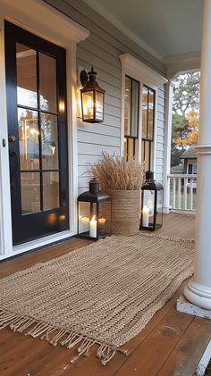 the front porch is decorated with lanterns and jute rugs for an inviting welcome