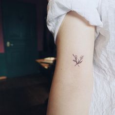 a small flower tattoo on the left arm