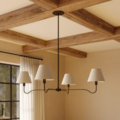 a chandelier hanging from the ceiling in a dining room with white linen shades