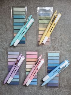 four different colored pens sitting on top of each other next to some pencils and markers