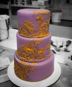 a three tiered cake with yellow and purple designs on it's sides in a kitchen