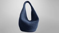 a blue crocheted bag hanging from a hook on a gray wall with the handles down