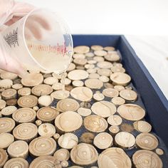 a person pouring something into a container filled with wood slices