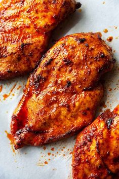 three pieces of chicken sitting on top of a piece of paper covered in seasoning