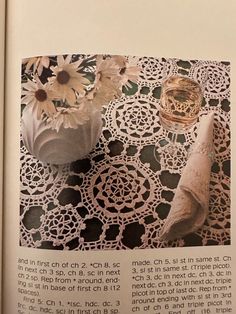 an open book with crocheted doily and vases on it's page