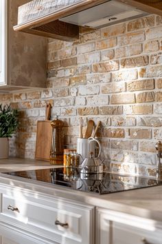 a kitchen with white cabinets and brick wall