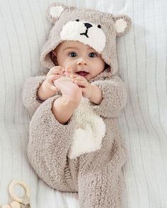 a baby in a bear costume laying on a bed