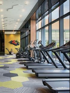 there are many treadmills lined up in the gym area with windows looking out onto the street