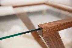 a glass top coffee table with an iron bar in the middle and wood frame around it